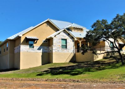 New Braunfels Custom Homes - rock and stucco home with silver metal roof in Vintage Oaks Subdivision in New Braunfels Texas