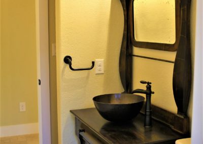 Dark wood antique bath vanity cabinet with vessel sink and bronze faucet