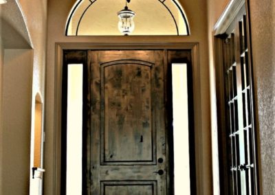 Custom home foyer with dark alder front door sidelites barrel wood ceiling and wood floor