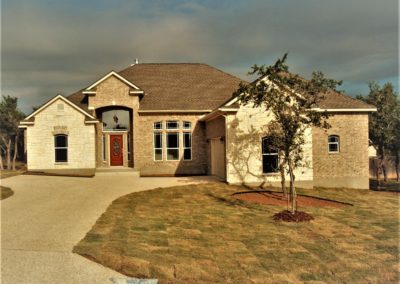 Tan Brick and White Rock Home with gray shingle roof