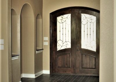 Custom Home Foyer Design with arched double entry doors and wall niches