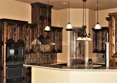 Dark Knotty Alder Cabinets with bronze hammered tin backsplash above granite countertops
