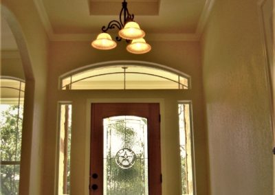 Home entry foyer with tray ceiling and wood Texas star glass door