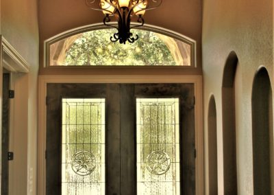 Custom Home Foyer with wood barrel ceiling, double leaded glass front doors, arched window and 3 art niches