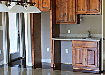 Gray Stained Concrete Floor in gameroom with rustic alder cabinets and wet bar.