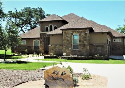 Texas Hill Country Tuscan style home with tan stucco and multi colored rock exterior