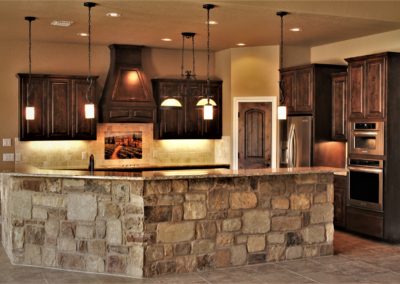 Rustic Knotty Alder Cabinets. Kitchen with dark cabinets granite countertops and rock barwall