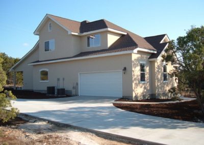 Two story tan stucco home with dark brown shingle roof