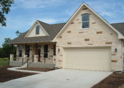 Texas Hill Country Rock Home. White and brown rock ranch style home with dark gray shingle roof