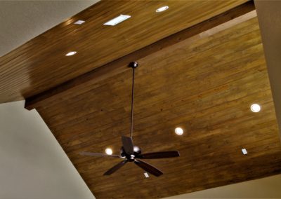 vaulted wood ceiling with ceiling fan and can lights