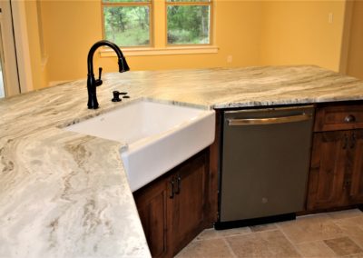 White farmhouse single bowl kitchen sink with gray marble countertop and bronze faucet