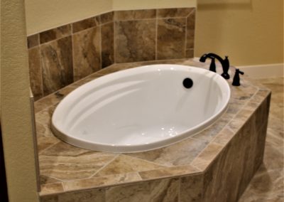 White master bath garden tub and roman tub faucet in brown tiled tub platform