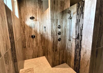 Large walk-in shower with bench seat, multiple showerheads and body sprays.