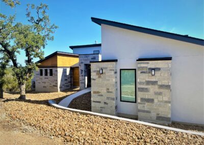 modern home design with grey stucco, cedar siding and multi colored rock on exterior.